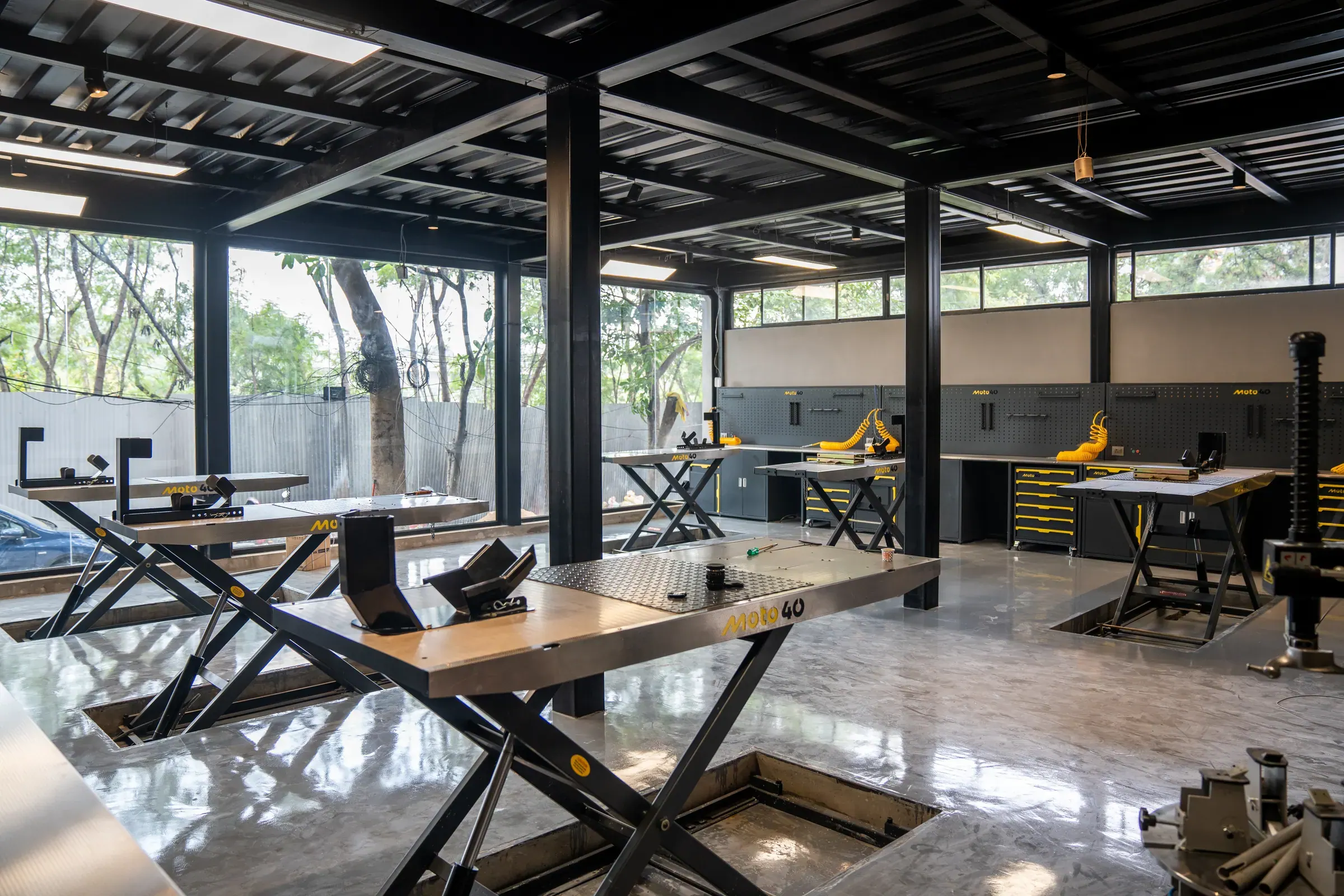 A Moto40 service bay in daylight, scissor lift raised, greenery through the windows